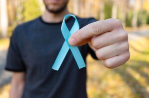 hombre sosteniendo un lazo azul, símbolo de la concientización sobre la salud prostática y el cáncer de próstata